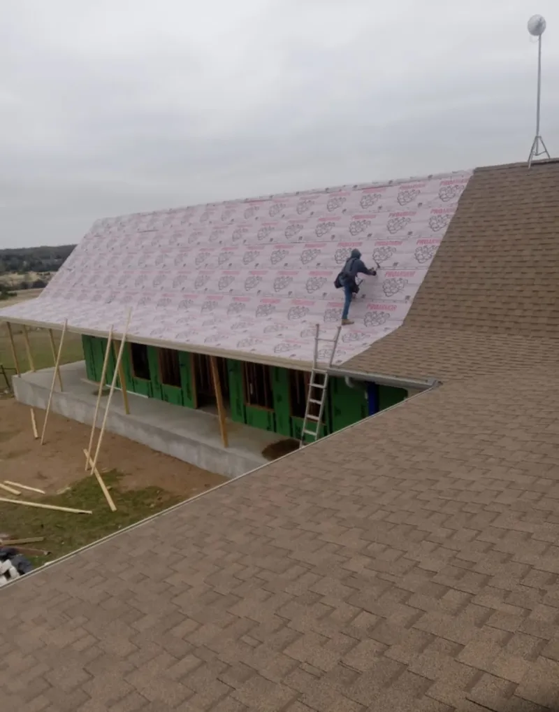 Worker preparing underlayment for a metal roof installation in Hamtramck